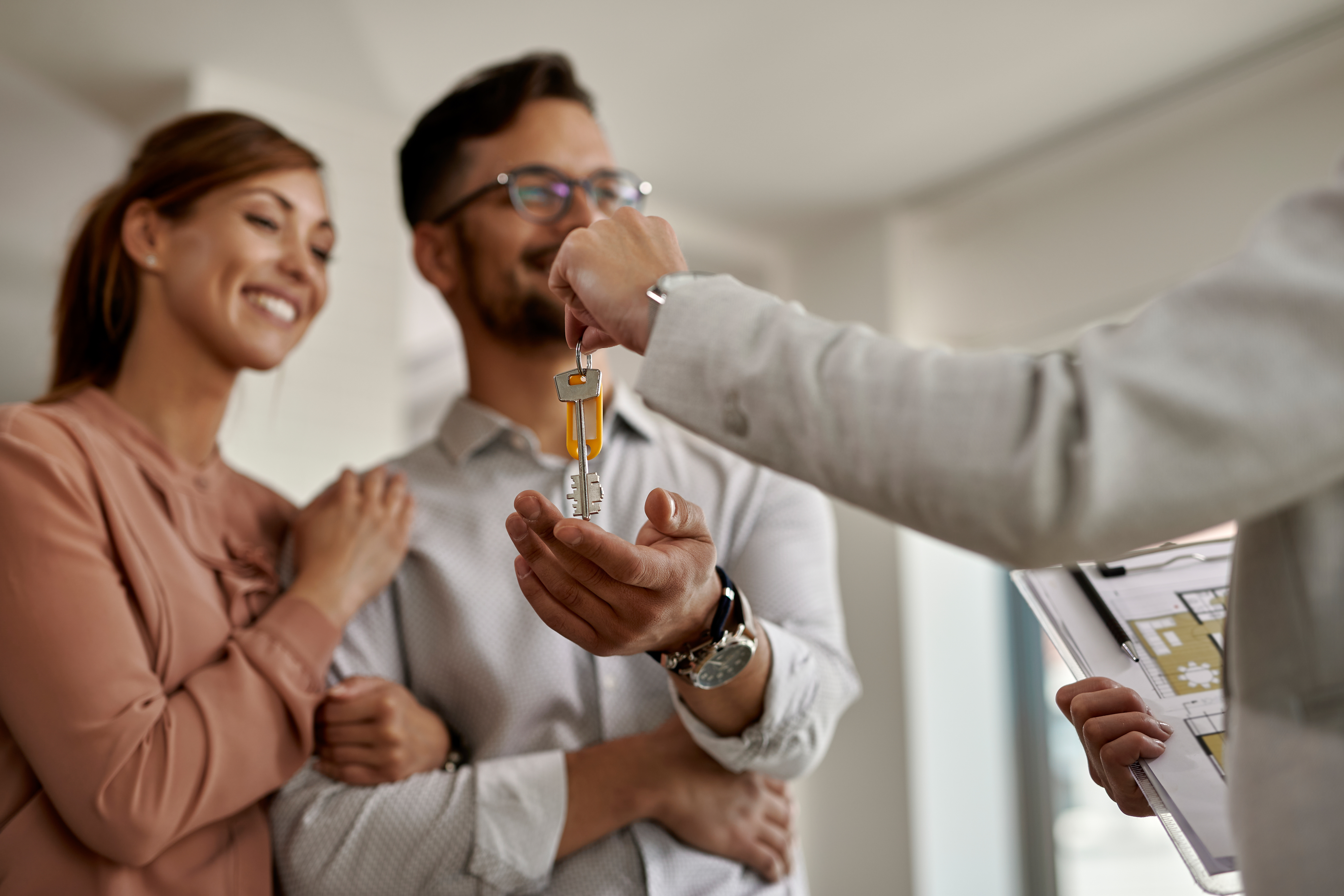 closeup real estate agent giving couple keys their new home (1)